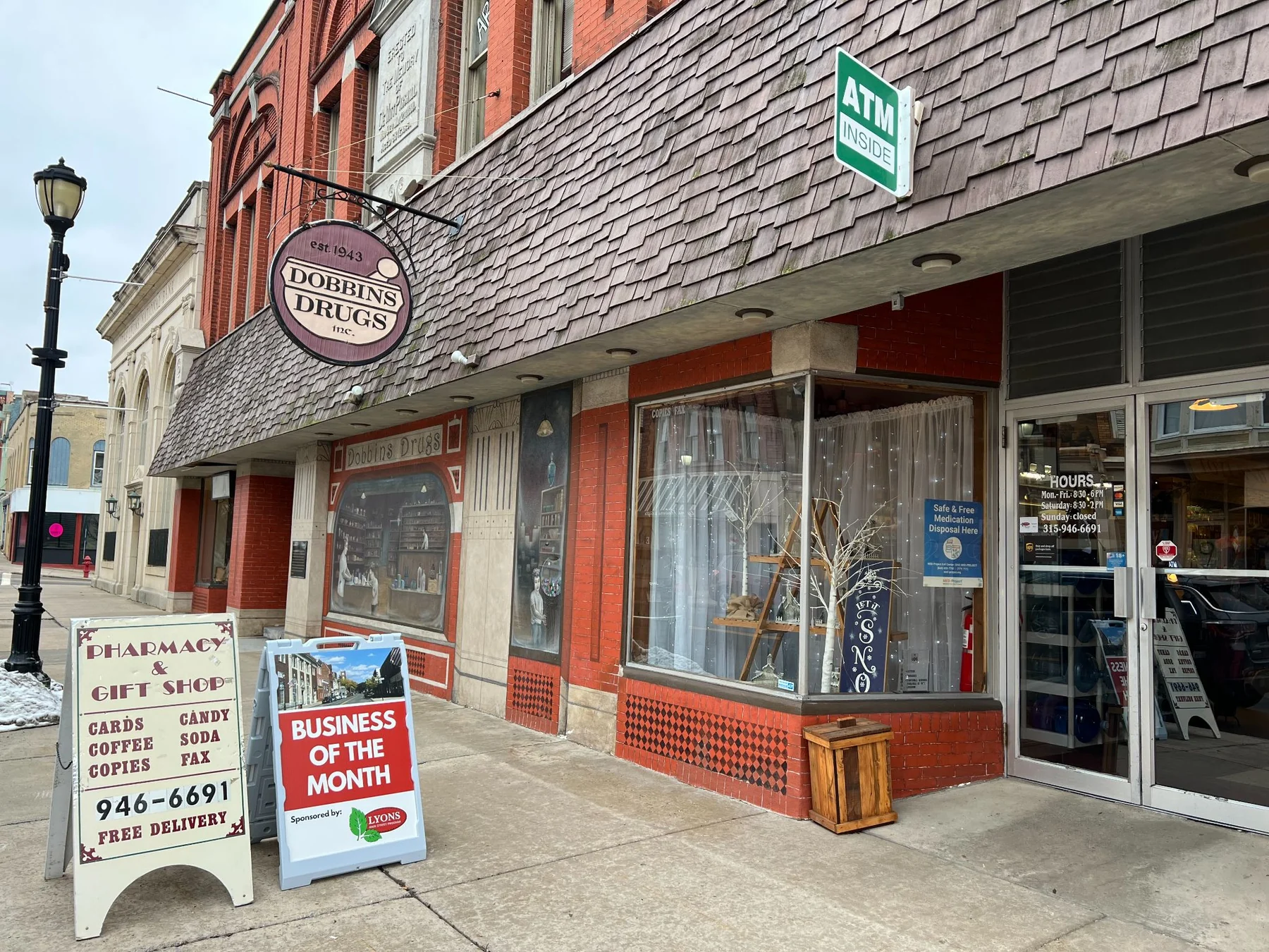 The real Dobbins Drugs storefront and hanging sign on William Street in Lyons
